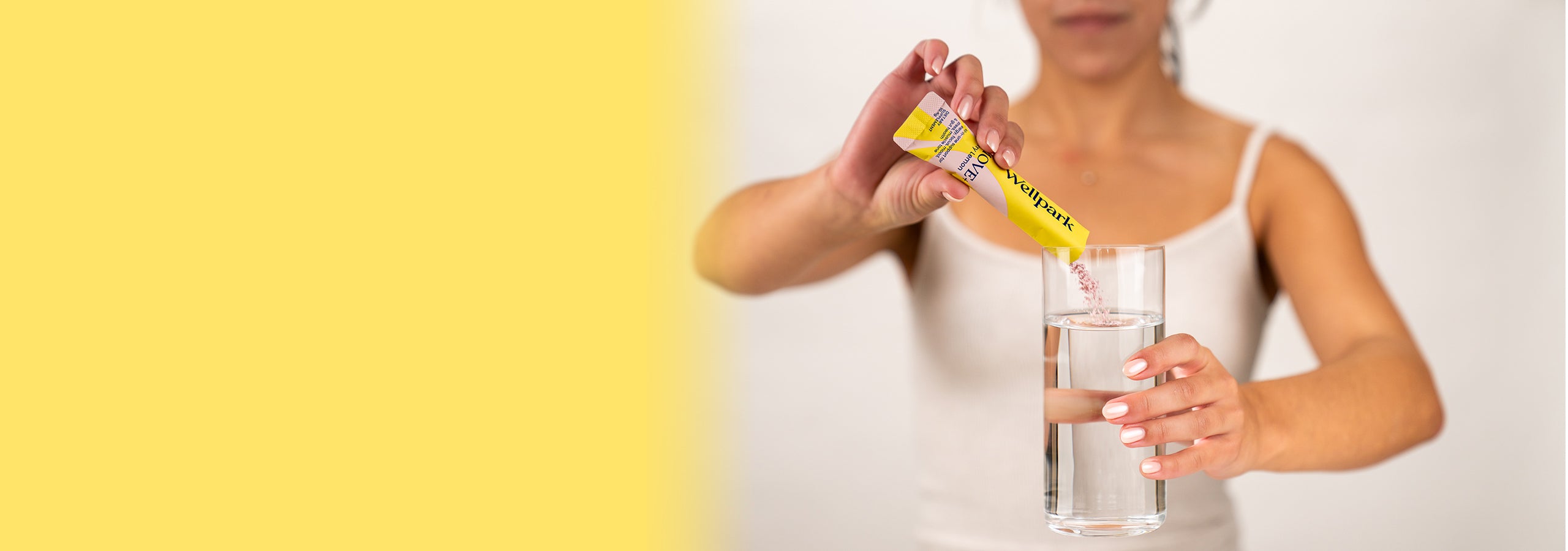 Woman adding sachet of Wellpark MOVE+ to a glass of water