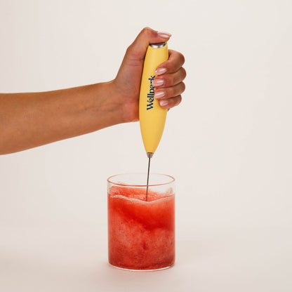 Hand mixing Wellpark MOVE+ Berry Lemon into water with an electric whisk