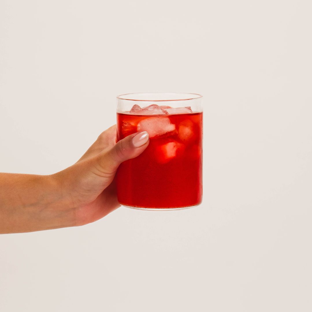 Hand holding glass of Wellpark MOVE+ creatine formula for women