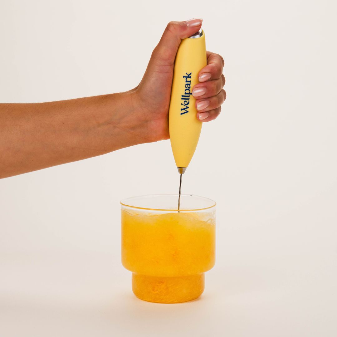 Hand mixing Wellpark MOVE+ Tropical into water with an electric whisk