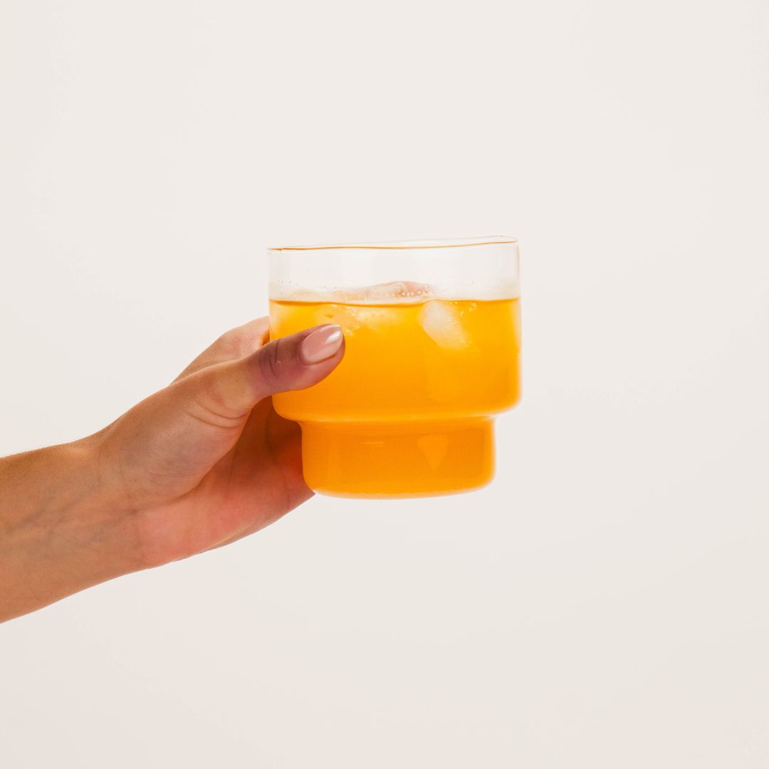 Hand holding glass of Wellpark MOVE+ creatine formula for women
