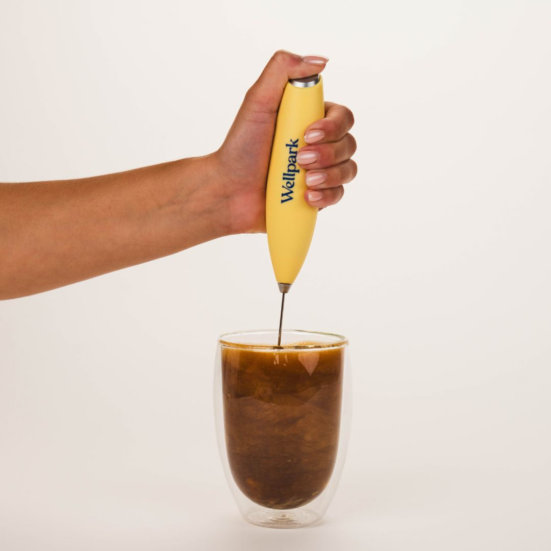 Hand mixing Wellpark MOVE+ into a coffee with electric whisk