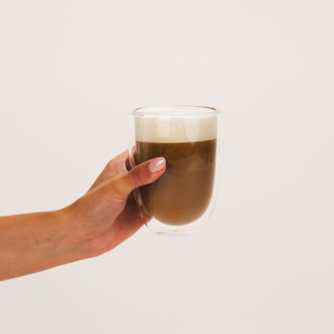 Hand holding coffee made with Wellpark MOVE+ creatine formula